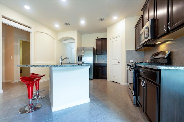 13903 Cantata Ln, Austin, TX 78660 - kitchen featuring stainless steel appliances, dark brown cabinetry, tasteful backsplash, light stone countertops, and recessed lighting