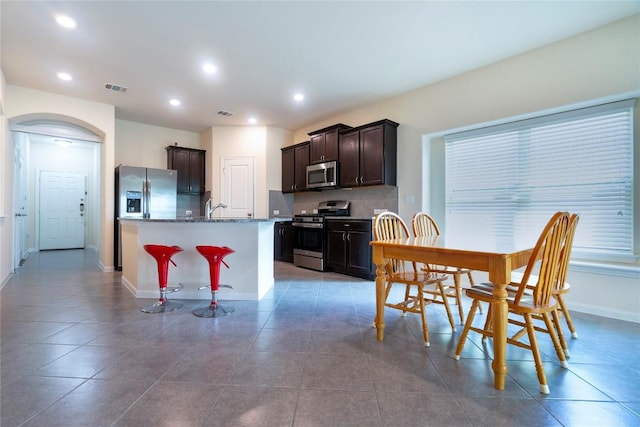 13903 Cantata Ln, Austin, TX 78660 - kitchen featuring stainless steel appliances, backsplash, dark brown cabinets, tile patterned flooring, and recessed lighting