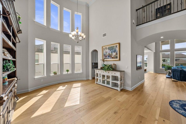 4509 Port Bari Dr, Leander, TX 78641 - entryway featuring arched walkways, a towering ceiling, a chandelier, wood-type flooring, and ornamental molding