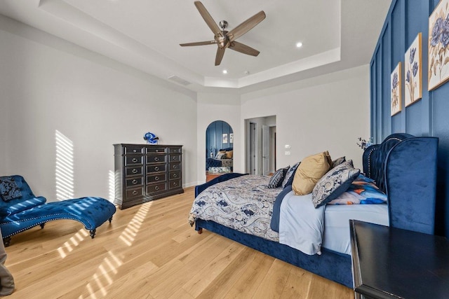 4509 Port Bari Dr, Leander, TX 78641 - bedroom with a tray ceiling, arched walkways, light wood-type flooring, recessed lighting, and ceiling fan