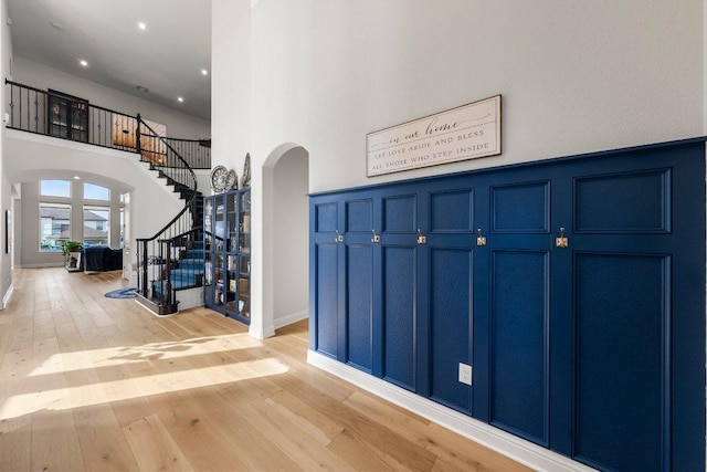 4509 Port Bari Dr, Leander, TX 78641 - entryway with arched walkways, stairs, light wood-style flooring, a towering ceiling, and recessed lighting