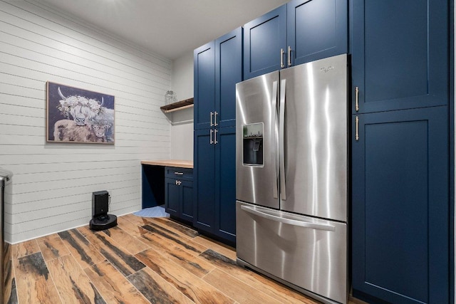4509 Port Bari Dr, Leander, TX 78641 - kitchen with stainless steel refrigerator with ice dispenser, blue cabinetry, open shelves, butcher block countertops, and wooden walls