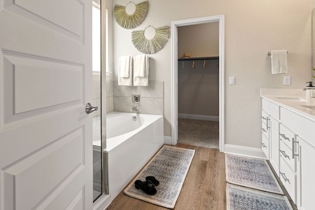 16941 Aventura Ave, Pflugerville, TX 78660 - bathroom featuring a bath, wood finished floors, double vanity, and a spacious closet