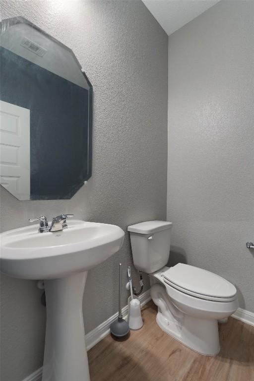 12003 Curlin Cv, Buda, TX 78610 - half bathroom with wood finished floors and a textured wall