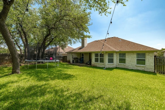 198 Sheridan Loop, Belton, TX 76513 - rear view of house with a chimney, a trampoline, stone siding, a fenced backyard, and roof with shingles