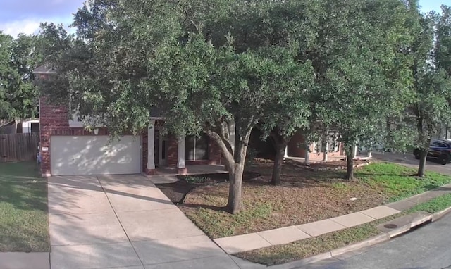 17714 Limpia Crk, Round Rock, TX 78664 - view of property hidden behind natural elements featuring concrete driveway, brick siding, and a garage