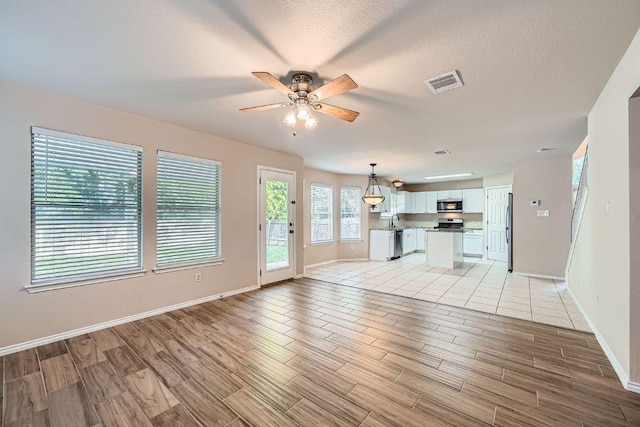 17714 Limpia Crk, Round Rock, TX 78664 - unfurnished living room featuring a ceiling fan, light wood finished floors, and a textured ceiling