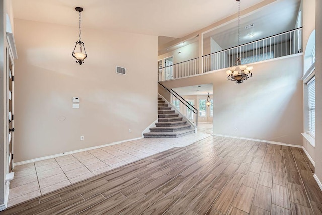 17714 Limpia Crk, Round Rock, TX 78664 - unfurnished living room featuring a chandelier, wood tiled floors, a high ceiling, and stairway