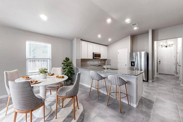 12301 Amber Lynn Path, Manor, TX 78653 - kitchen with appliances with stainless steel finishes, a peninsula, light stone counters, recessed lighting, and lofted ceiling