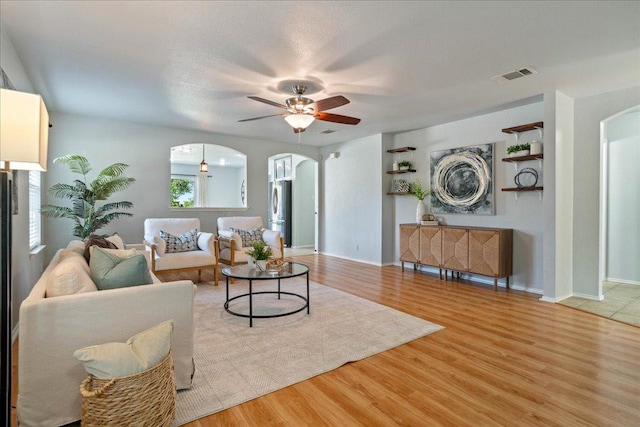 2102 Garrison Dr, Leander, TX 78641 - living room with arched walkways, a ceiling fan, and wood finished floors