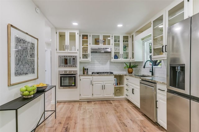 7806 Mullen Dr, Austin, TX 78757 - kitchen with stainless steel appliances, under cabinet range hood, tasteful backsplash, white cabinetry, and light stone counters
