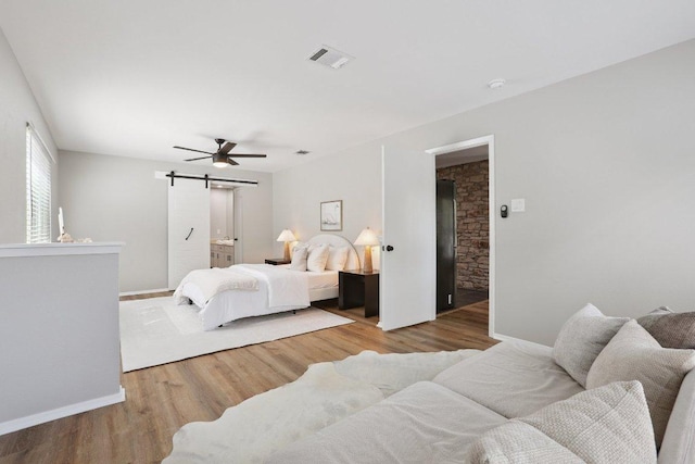 13101 Silver Creek Dr, Austin, TX 78727 - bedroom with a barn door, wood finished floors, and ceiling fan