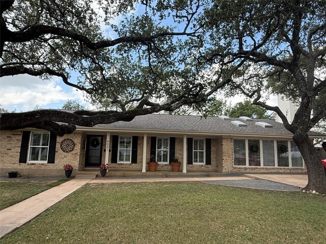 4001 Greystone Dr, Austin, TX 78731 - ranch-style home with a front yard, brick siding, and roof with shingles