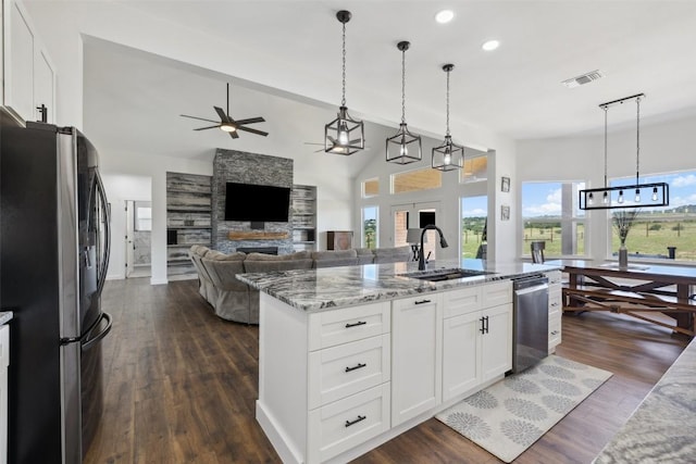 105 Mesa Grande Ct, Marble Falls, TX 78654 - kitchen featuring stainless steel appliances, a fireplace, light stone countertops, a ceiling fan, and white cabinetry