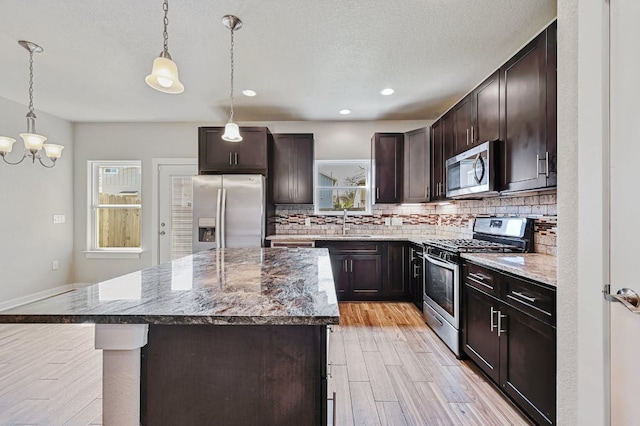 3303 Elija St Unit A & B, Austin, TX 78745 - kitchen featuring stainless steel appliances, tasteful backsplash, a kitchen island, dark brown cabinets, and a chandelier