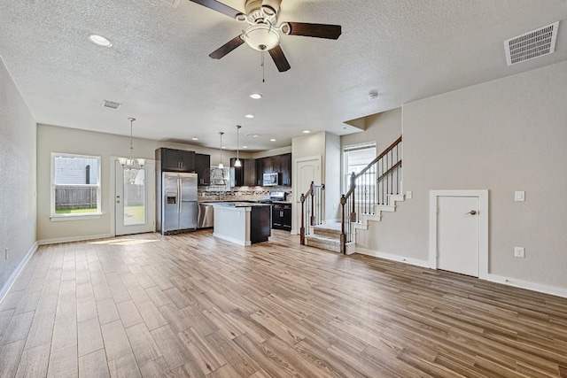 3303 Elija St Unit A & B, Austin, TX 78745 - unfurnished living room with light wood-type flooring, a ceiling fan, healthy amount of natural light, a textured ceiling, and stairs