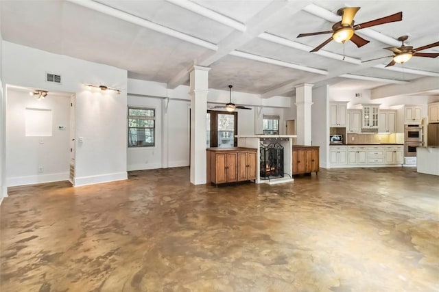 208 Old Potato Rd, Paige, TX 78659 - unfurnished living room featuring ceiling fan, concrete floors, beam ceiling, ornate columns, and a lit fireplace