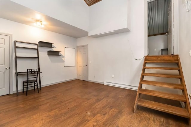 208 Old Potato Rd, Paige, TX 78659 - unfurnished living room featuring a baseboard heating unit, wood finished floors, stairs, and a high ceiling