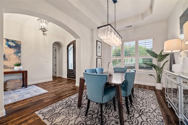 3810 Pawnee Pass, Austin, TX 78738 - dining room featuring a chandelier, arched walkways, dark wood-type flooring, and a raised ceiling