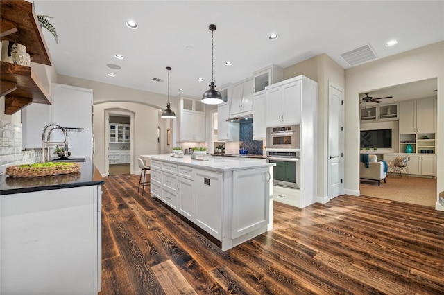 3810 Pawnee Pass, Austin, TX 78738 - kitchen with arched walkways, dark wood-type flooring, white cabinets, a ceiling fan, and backsplash