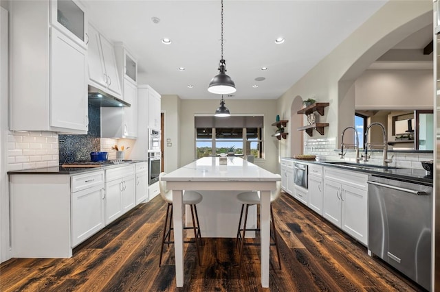 3810 Pawnee Pass, Austin, TX 78738 - kitchen with appliances with stainless steel finishes, arched walkways, a center island, recessed lighting, and dark wood-type flooring