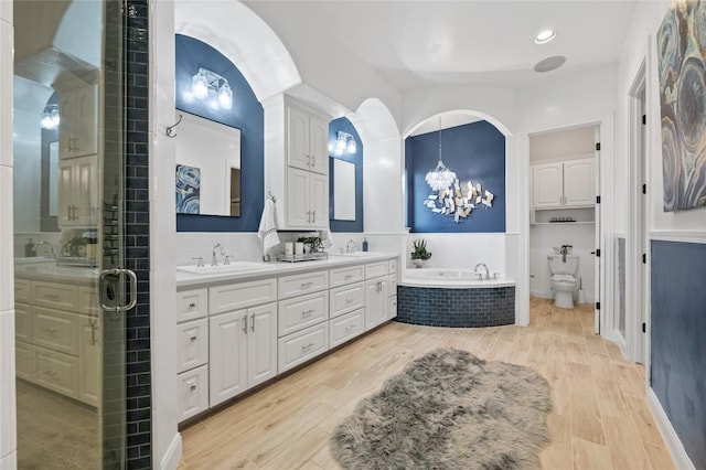 3810 Pawnee Pass, Austin, TX 78738 - full bath with double vanity, a chandelier, a garden tub, wood finished floors, and a stall shower