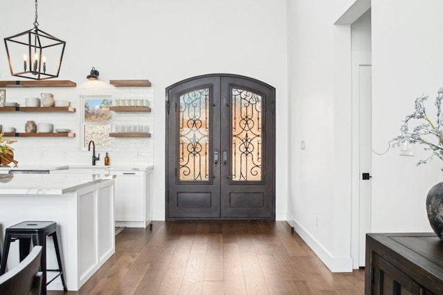 169 Tall Forest Dr, Bastrop, TX 78602 - bar area featuring french doors, dark wood finished floors, arched walkways, pendant lighting, and decorative backsplash