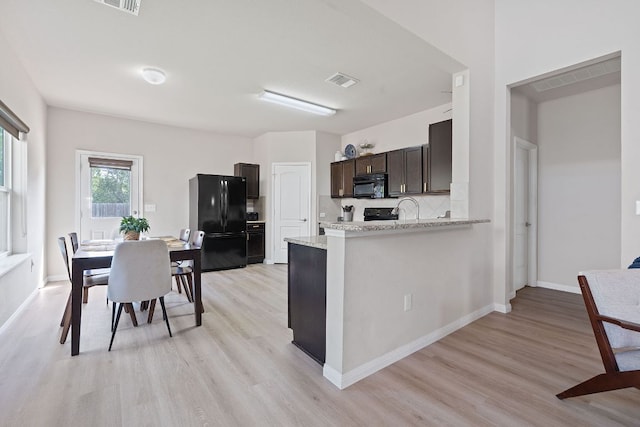 3526 Wickham Ln, Austin, TX 78725 - kitchen featuring black appliances, light wood-style flooring, dark brown cabinetry, and light stone countertops