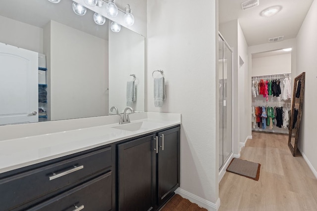 3526 Wickham Ln, Austin, TX 78725 - full bathroom featuring wood finished floors, vanity, a stall shower, and a walk in closet