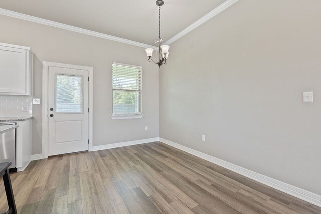103 W Tomlinson St, Florence, TX 76527 - unfurnished dining area with light wood-style floors, a chandelier, and crown molding