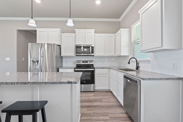 103 W Tomlinson St, Florence, TX 76527 - kitchen featuring stainless steel appliances, crown molding, white cabinetry, backsplash, and decorative light fixtures
