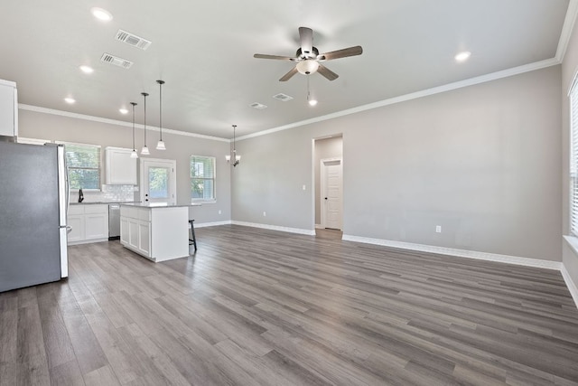 103 W Tomlinson St, Florence, TX 76527 - unfurnished living room featuring ceiling fan, recessed lighting, wood finished floors, a chandelier, and ornamental molding