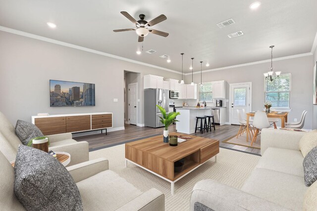 103 W Tomlinson St, Florence, TX 76527 - living area featuring wood finished floors, a ceiling fan, recessed lighting, crown molding, and a chandelier