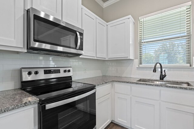 103 W Tomlinson St, Florence, TX 76527 - kitchen featuring appliances with stainless steel finishes, ornamental molding, white cabinets, backsplash, and light stone counters