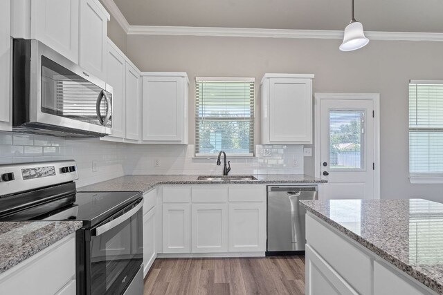 103 W Tomlinson St, Florence, TX 76527 - kitchen featuring appliances with stainless steel finishes, crown molding, white cabinets, light wood-type flooring, and backsplash