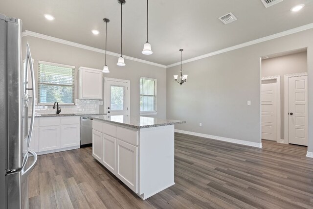 103 W Tomlinson St, Florence, TX 76527 - kitchen with appliances with stainless steel finishes, dark wood-style flooring, white cabinetry, a kitchen island, and decorative backsplash