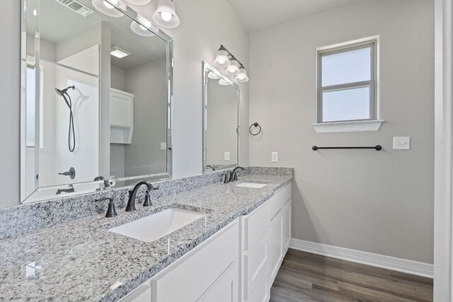 103 W Tomlinson St, Florence, TX 76527 - full bathroom featuring double vanity, wood finished floors, and a shower