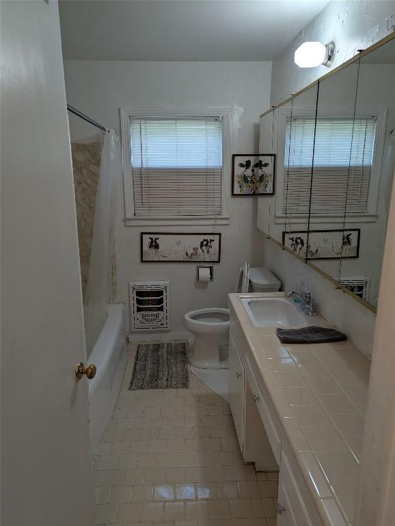 606 Scurry St, Austin, TX 78753 - full bathroom featuring heating unit, vanity, tile patterned floors, and shower / bath combination with curtain
