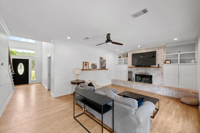 707 Malabar St, Lakeway, TX 78734 - living area with light wood finished floors, ceiling fan, built in shelves, ornamental molding, and a brick fireplace