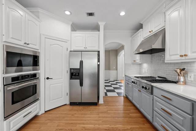707 Malabar St, Lakeway, TX 78734 - kitchen with appliances with stainless steel finishes, under cabinet range hood, arched walkways, ornamental molding, and white cabinets