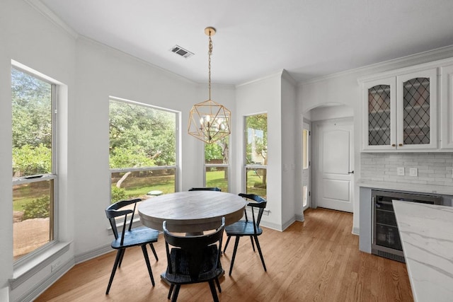 707 Malabar St, Lakeway, TX 78734 - dining space with ornamental molding, a chandelier, light wood finished floors, beverage cooler, and arched walkways