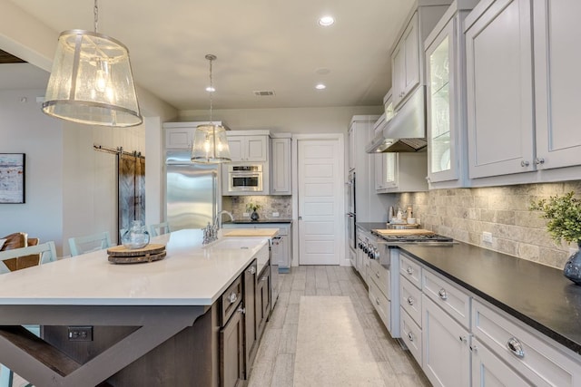 2800 Crystal Falls Pkwy, Leander, TX 78641 - kitchen featuring appliances with stainless steel finishes, decorative backsplash, recessed lighting, decorative light fixtures, and a kitchen island with sink