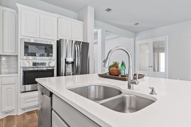 3604 Mercer Rd, Georgetown, TX 78628 - kitchen featuring stainless steel appliances, light countertops, white cabinets, wood finished floors, and french doors