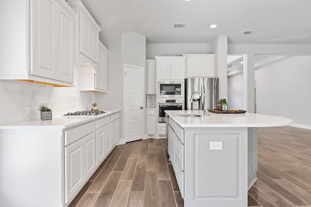 3604 Mercer Rd, Georgetown, TX 78628 - kitchen with stainless steel appliances, wood finished floors, white cabinets, a center island with sink, and recessed lighting