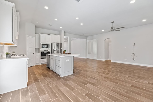 3604 Mercer Rd, Georgetown, TX 78628 - kitchen featuring appliances with stainless steel finishes, arched walkways, open floor plan, a ceiling fan, and white cabinetry