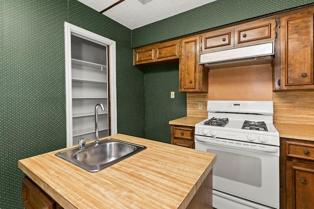 2403 N Shields Dr, Austin, TX 78727 - kitchen with white gas range, wallpapered walls, under cabinet range hood, wooden counters, and brown cabinets