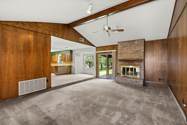 2403 N Shields Dr, Austin, TX 78727 - unfurnished living room with wood walls, ceiling fan, carpet, and a brick fireplace
