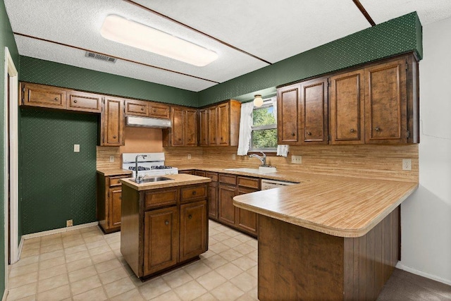 2403 N Shields Dr, Austin, TX 78727 - kitchen featuring under cabinet range hood, light countertops, a kitchen island, and backsplash