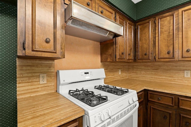 2403 N Shields Dr, Austin, TX 78727 - kitchen with white gas range oven, under cabinet range hood, light countertops, and wallpapered walls