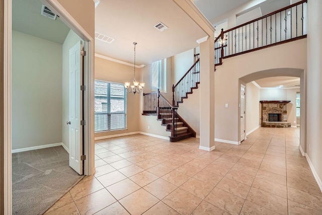 3914 Remington Rd, Cedar Park, TX 78613 - foyer entrance featuring arched walkways, a stone fireplace, a chandelier, light tile patterned flooring, and ornamental molding
